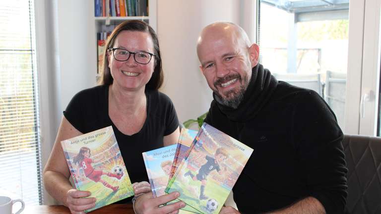 Antje und Christof aus Dreieich mit mehreren personalisierten ballstories-Büchern in der Hand